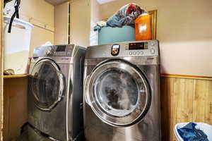 Laundry room with washing machine and dryer, wood walls, and cabinets