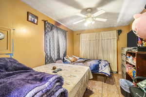 Bedroom with ceiling fan and a textured ceiling