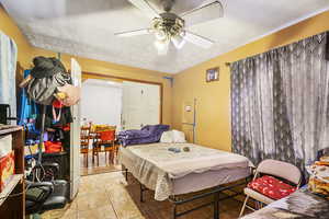 Bedroom featuring ceiling fan, a textured ceiling, and light tile patterned floors