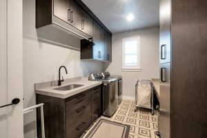 Laundry room with sink, separate washer and dryer, and cabinets