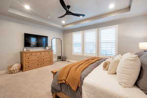 Bedroom featuring ceiling fan, carpet, and a tray ceiling