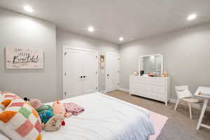 Carpeted bedroom featuring multiple closets