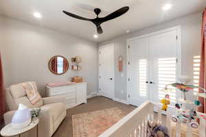 Bedroom featuring ceiling fan, carpet, and a crib