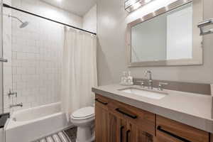 Full bathroom with shower / bath combo with shower curtain, toilet, tile patterned floors, and vanity