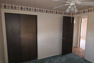 Unfurnished bedroom featuring dark carpet, a closet, and ceiling fan