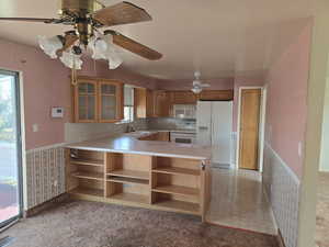 Kitchen featuring white appliances, light carpet, sink, kitchen peninsula, and ceiling fan