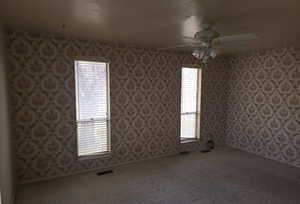 Unfurnished room with ceiling fan, a wealth of natural light, and carpet flooring