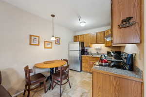 Kitchen featuring sink, hanging light fixtures, electric stove, and stainless steel fridge