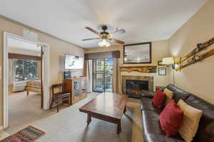 Carpeted living room with ceiling fan, a wall mounted AC, plenty of natural light, and a fireplace