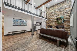 Living room featuring a fireplace, hardwood / wood-style floors, beamed ceiling, and a high ceiling