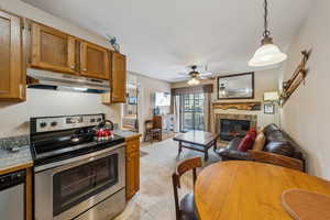 Kitchen featuring pendant lighting, ceiling fan, light tile patterned floors, a premium fireplace, and stainless steel appliances