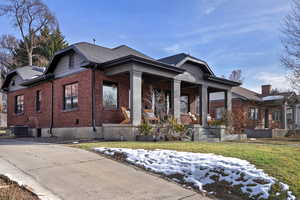 View of front facade featuring cooling unit, a lawn, and a porch