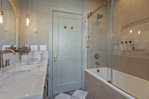 Bathroom featuring bath / shower combo with glass door, tile patterned floors, and vanity