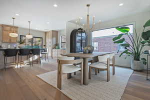 Dining area with light hardwood / wood-style floors and a notable chandelier