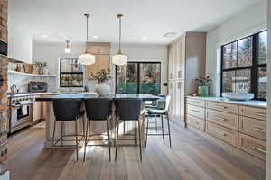 Kitchen with pendant lighting, plenty of natural light, light brown cabinets, and high end stove