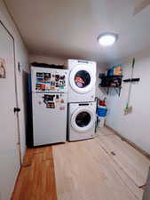 Washroom featuring stacked washer and dryer and light wood-type flooring