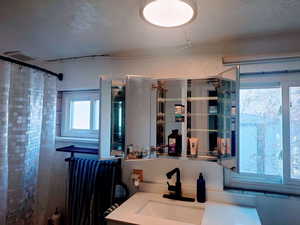 Bathroom featuring curtained shower, a textured ceiling, and vanity