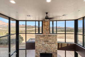 Unfurnished sunroom featuring ceiling fan, a mountain view, and plenty of natural light