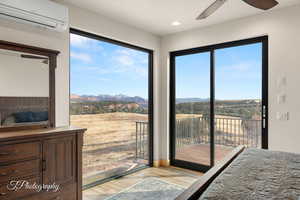 Bedroom featuring access to outside, ceiling fan, light wood-type flooring, a mountain view, and a wall unit AC