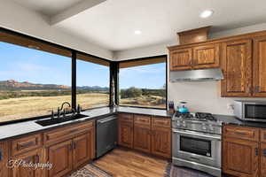 Kitchen with dark stone countertops, appliances with stainless steel finishes, dark wood-type flooring, a mountain view, and sink