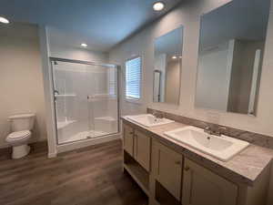 Bathroom with toilet, an enclosed shower, vanity, and hardwood / wood-style flooring