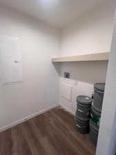 Clothes washing area with electric panel, dark wood-type flooring, and hookup for a washing machine