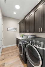 Clothes washing area with cabinets, light wood-type flooring, and independent washer and dryer