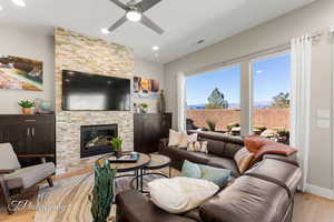 Living room with ceiling fan, a fireplace, and light hardwood / wood-style flooring