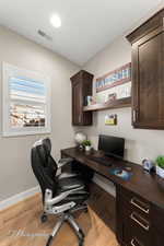 Office area with built in desk and light wood-type flooring