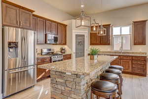 Kitchen featuring appliances with stainless steel finishes, decorative light fixtures, sink, a kitchen bar, and a kitchen island