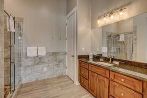 Bathroom featuring a shower with shower door and vanity