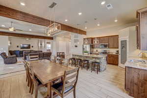 Dining area with ceiling fan, sink, and beamed ceiling