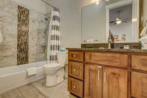 Full bathroom featuring shower / bath combo with shower curtain, toilet, ceiling fan, and vanity