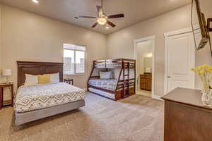 Carpeted bedroom with ceiling fan and ensuite bathroom