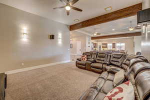 Home theater with ceiling fan and light colored carpet