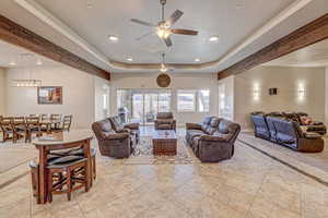 Living room featuring ceiling fan and a raised ceiling