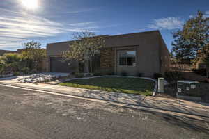 Pueblo revival-style home featuring a garage and a front yard