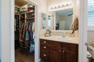 Bathroom featuring toilet, decorative backsplash, ceiling fan, and vanity