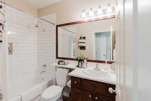 Full bathroom featuring shower / bath combo with shower curtain, toilet, and vanity