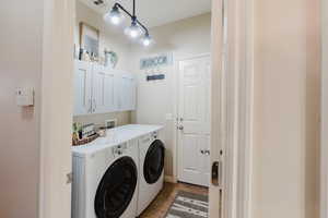 Laundry room featuring independent washer and dryer, cabinets, and tile patterned floors