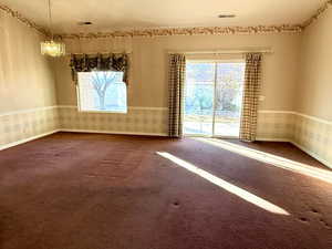 Empty room with carpet flooring and an inviting chandelier