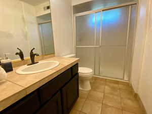 Bathroom with walk in shower, tile patterned flooring, vanity, and toilet