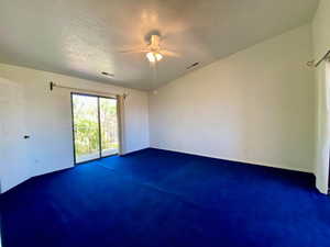 Carpeted spare room featuring a textured ceiling and ceiling fan