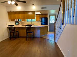 Kitchen featuring black appliances, a kitchen bar, kitchen peninsula, and wood-type flooring