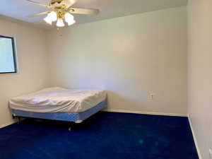 Unfurnished bedroom featuring carpet flooring, a textured ceiling, and ceiling fan