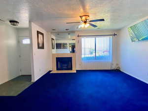 Unfurnished living room featuring a textured ceiling and ceiling fan