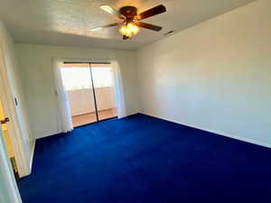 Carpeted empty room with a textured ceiling and ceiling fan