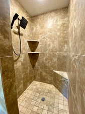 Bathroom featuring a tile shower and a textured ceiling