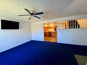 Unfurnished living room with a textured ceiling and ceiling fan