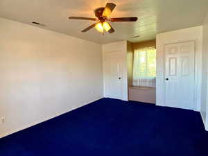 Unfurnished bedroom featuring ceiling fan, carpet, and a textured ceiling